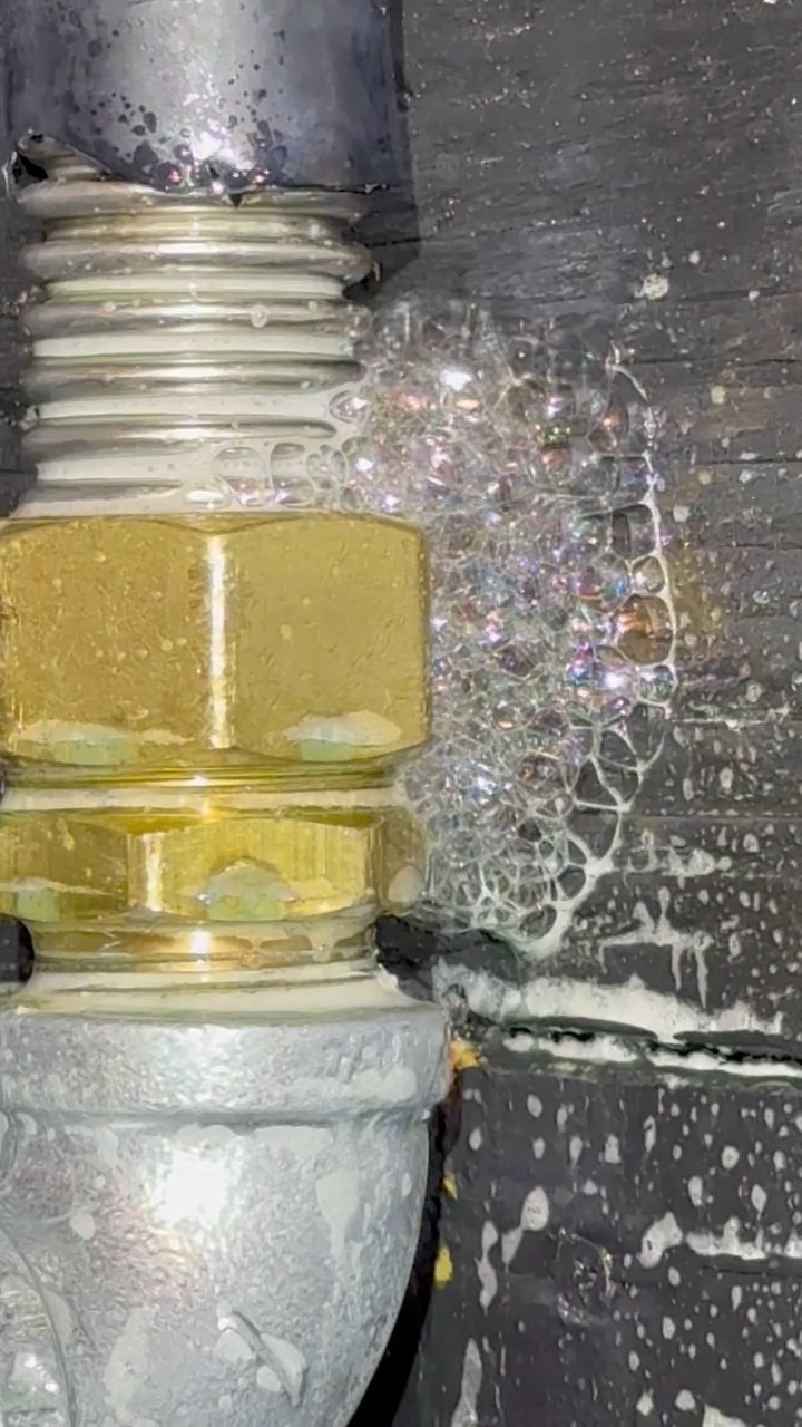 Video of soap solution bubbling at a gas pipe fitting, confirming the location of a gas leak