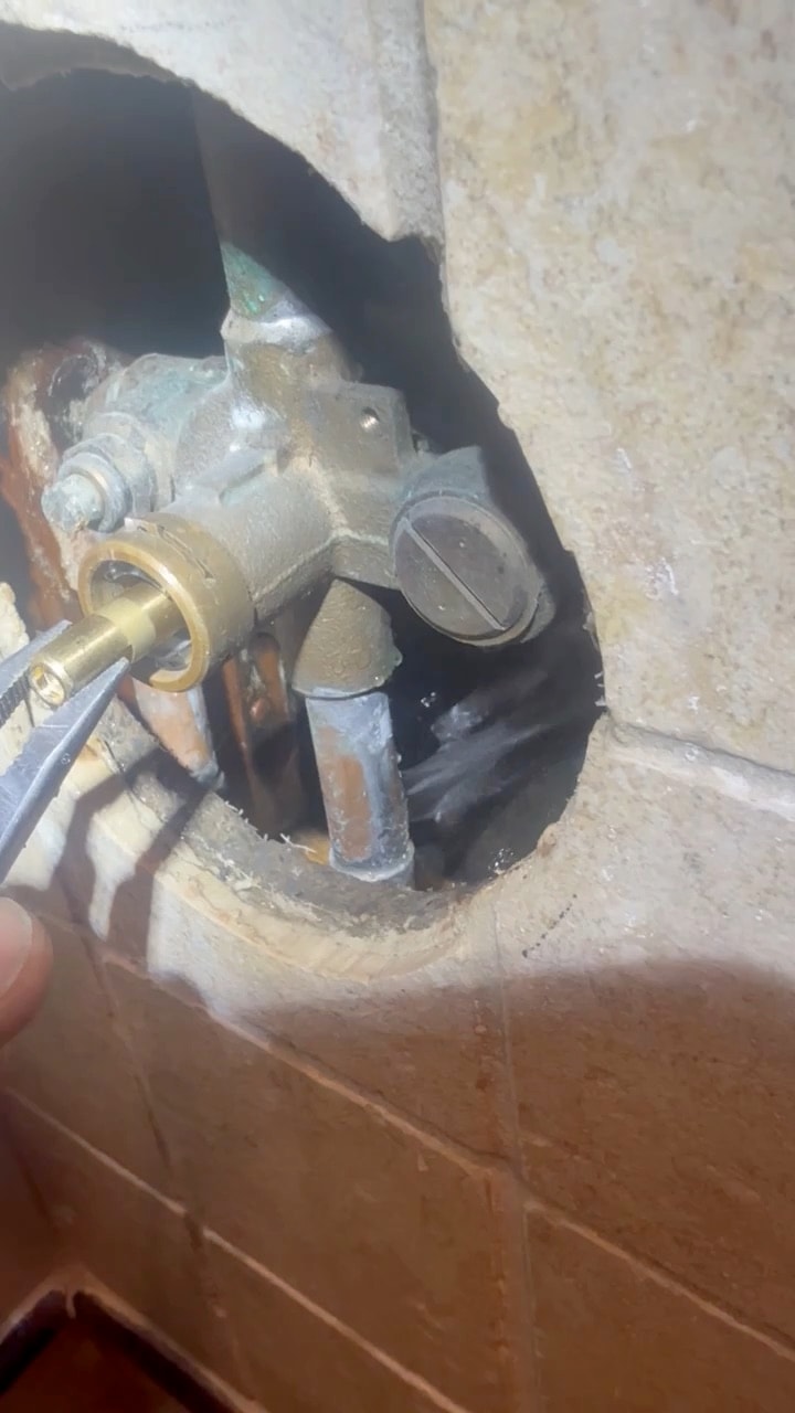 Video of a tub and shower valve reached through a single hole cut in a tiled wall to repair a leaking fitting