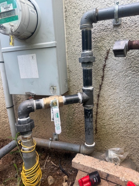 A new gas shut-off valve and black iron unions connected at an exterior gas meter