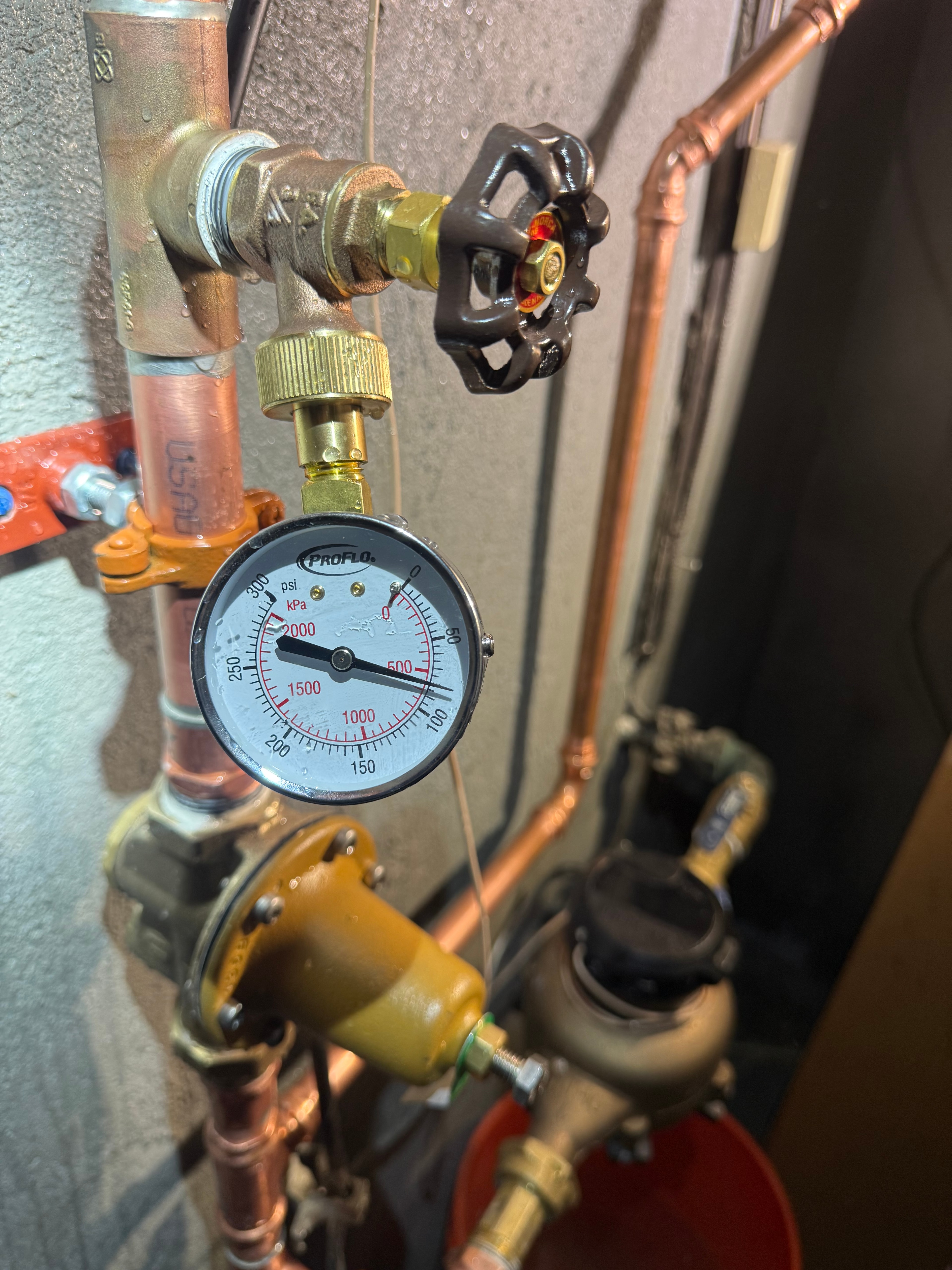A pressure gauge fitted on a copper line beside a brass pressure reducing valve