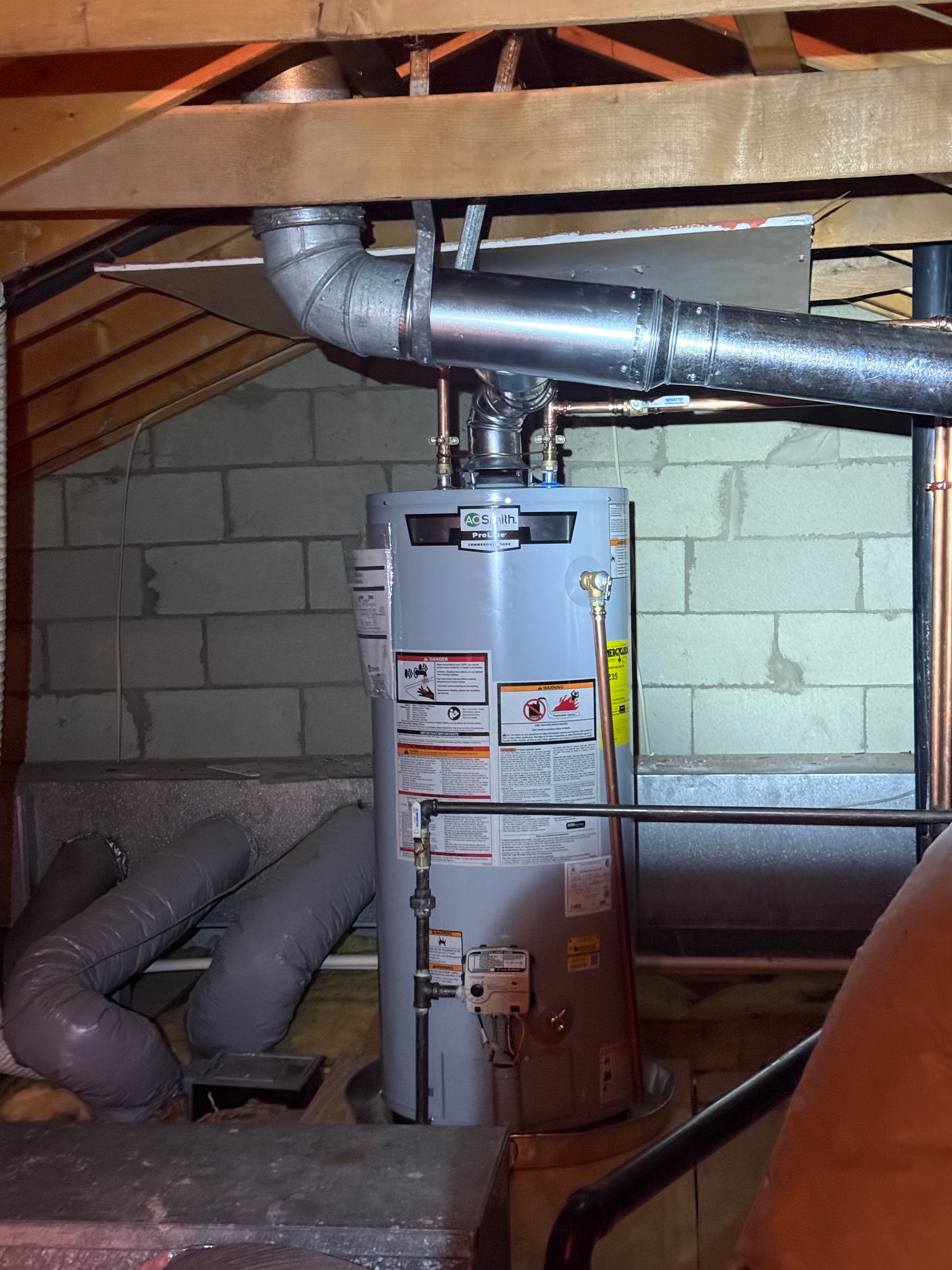 An A.O. Smith gas water heater installed in a basement with a new galvanised flue run