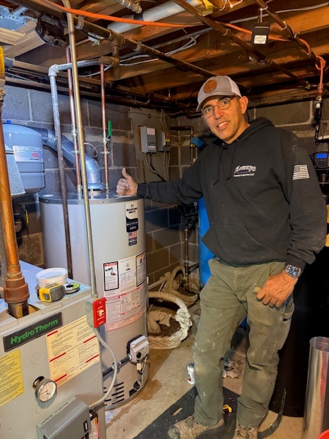 David beside a newly installed gas water heater next to an existing HydroTherm boiler