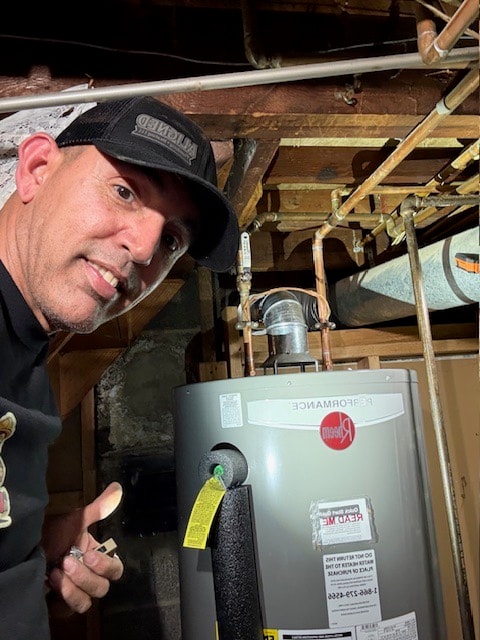 David checking the flue connection on a Rheem Performance gas water heater in a low basement