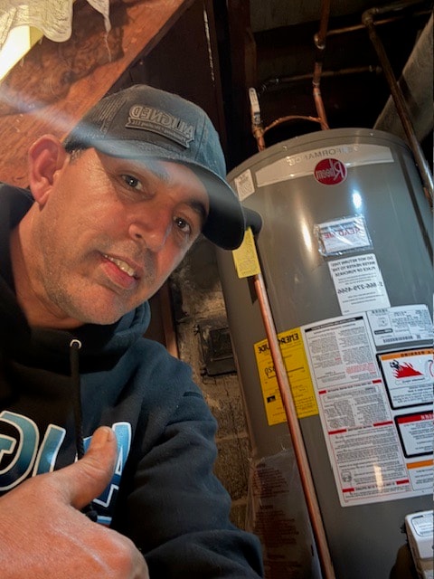 David beside a newly installed Rheem gas water heater in a basement