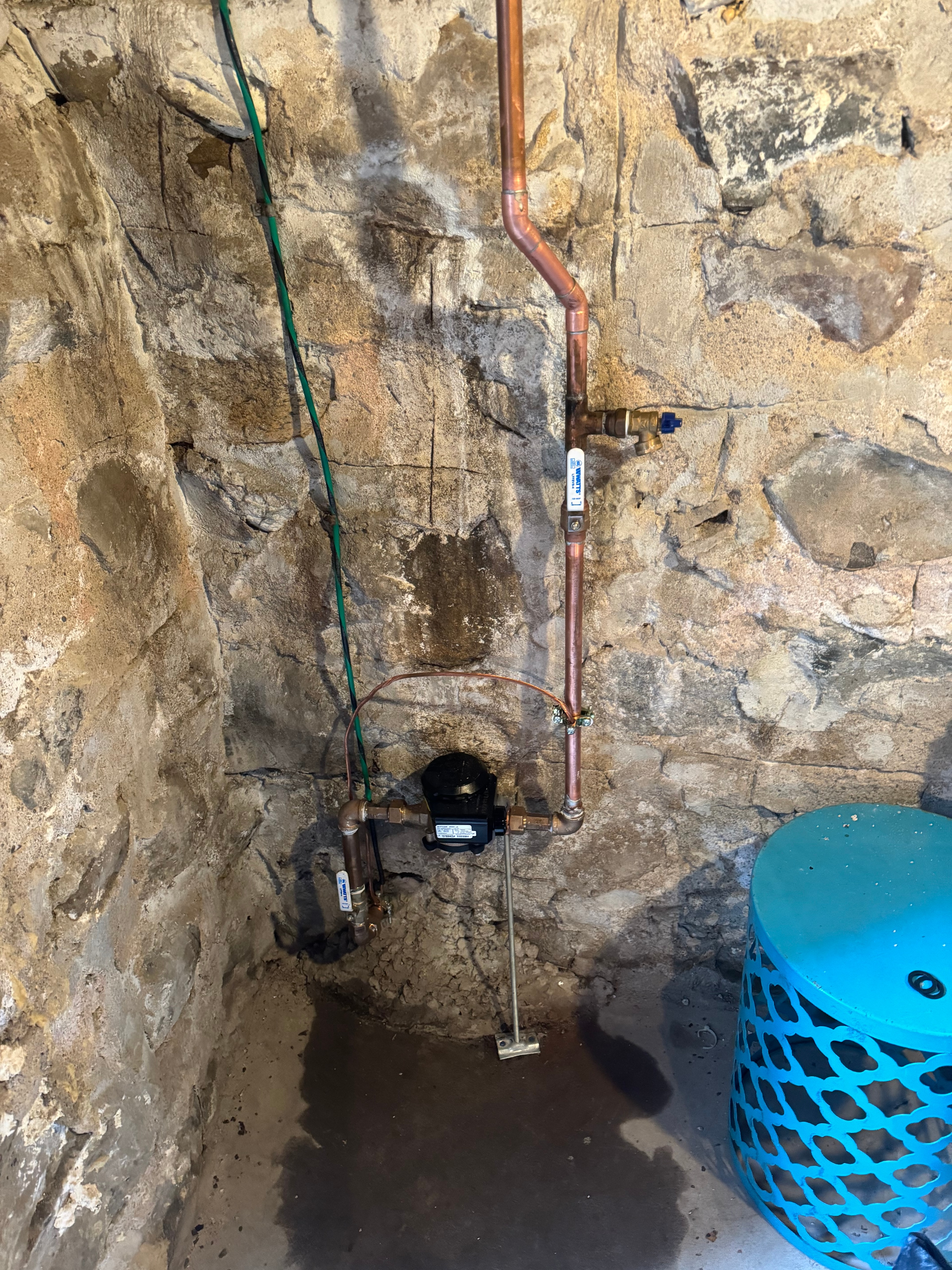 A water main shut-off and meter replaced on a stone foundation wall, run in new copper